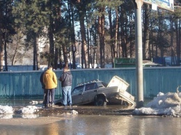 В Киеве так затопило дорогу, что машина провалилась под асфальт: появились фото