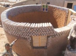 Парень строит дома, используя вместо кирпичей бутылки с песком