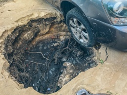 В Киеве машина зависла колесом над метровой ямой, вымытой после прорыва трубы