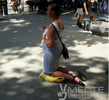 В центре Запорожья беременная девушка на коленях просит милостыню